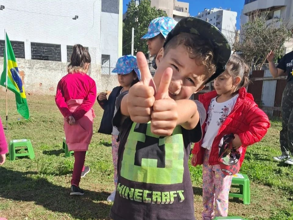 Imagem de criança fazendo sinal de ok com as duas mãos, em evento do projeto fome de amor caxias.